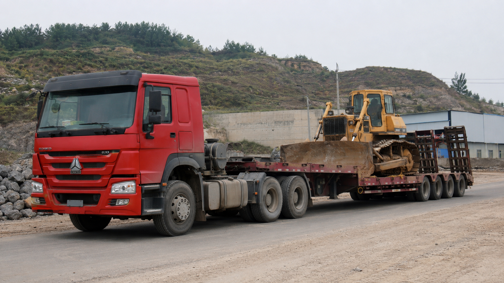 Low bed semi trailer transporting a bulldozer on a project road