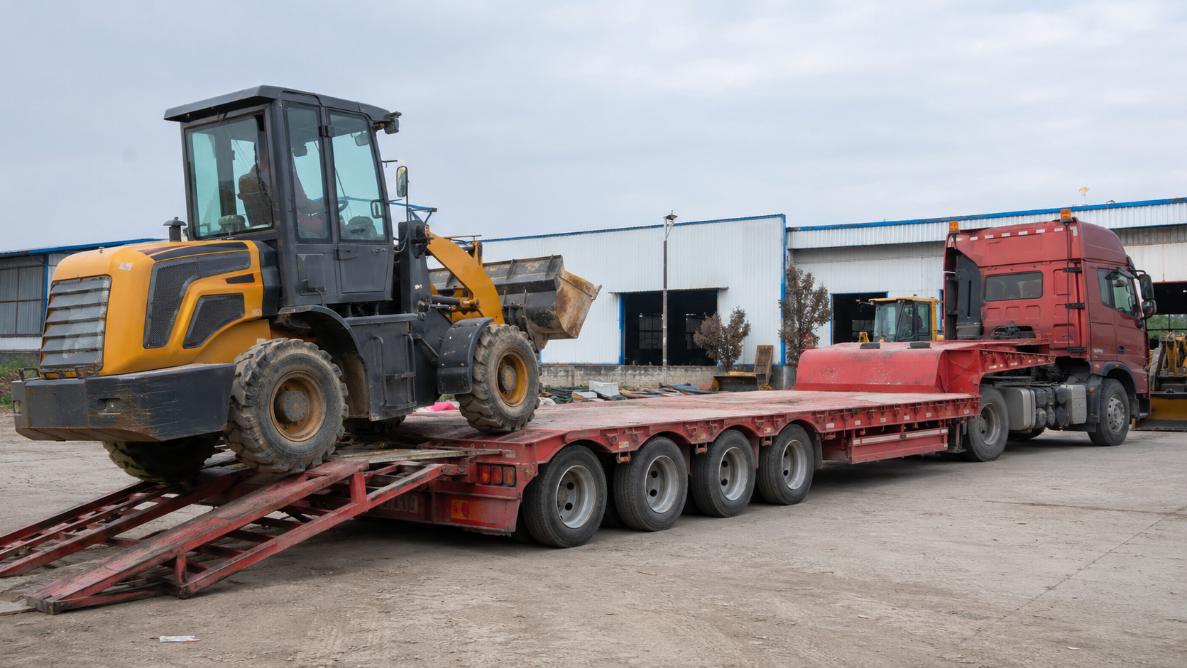 Wheel loader loading onto a low bed semi trailer ramp