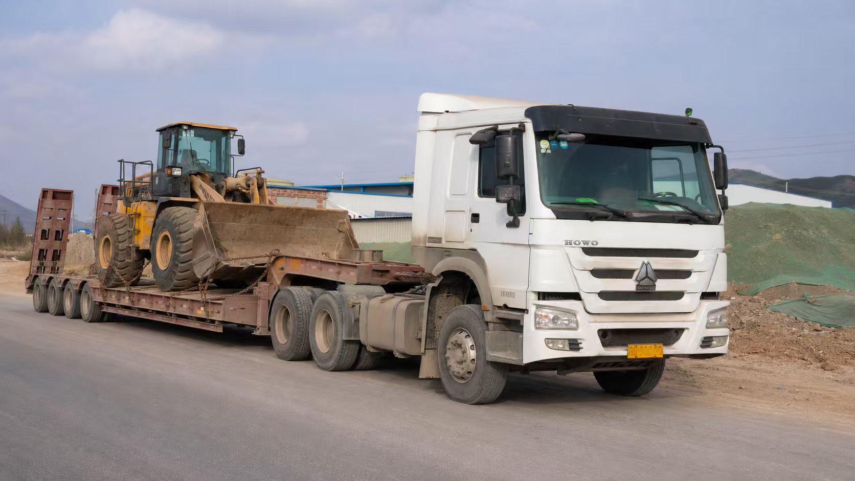 Tractor truck pulling a low bed semi trailer with a wheel loader