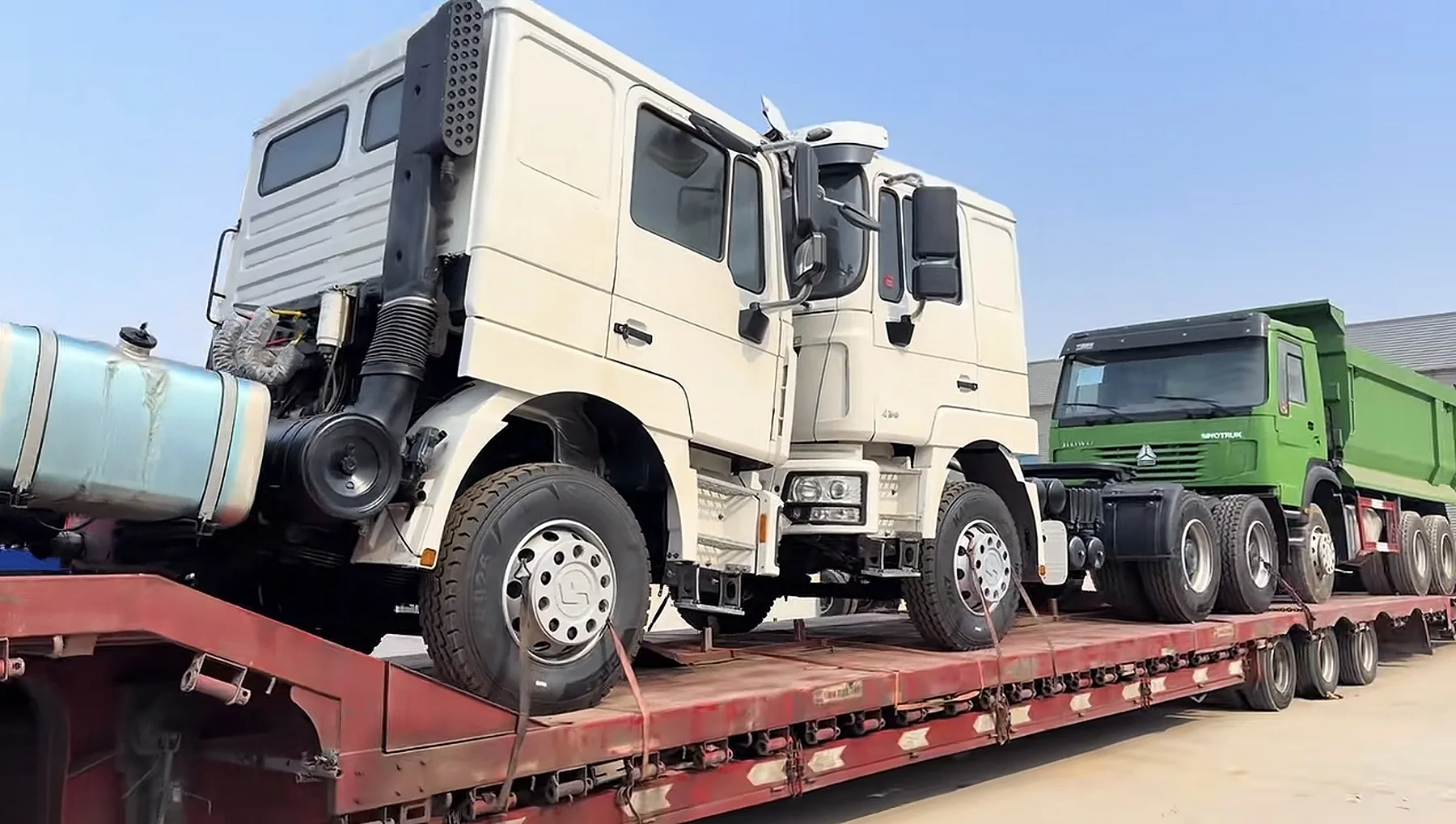Multiple used trucks secured on a trailer for shipment